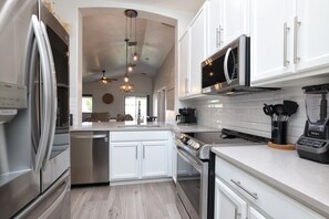 A modern kitchen with stainless steel appliances, white cabinetry, and a central island.