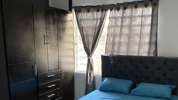 Une chambre à coucher comprenant un lit, une armoire et un téléviseur fixé au mur.