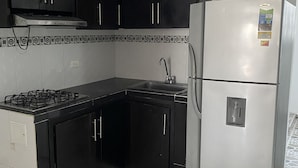 Une cuisine avec des meubles de couleur noire, un réfrigérateur en acier inoxydable et une cuisinière à gaz.