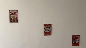 Un mur orné de trois enseignes au style rétro : un café, un garage et une station-service.