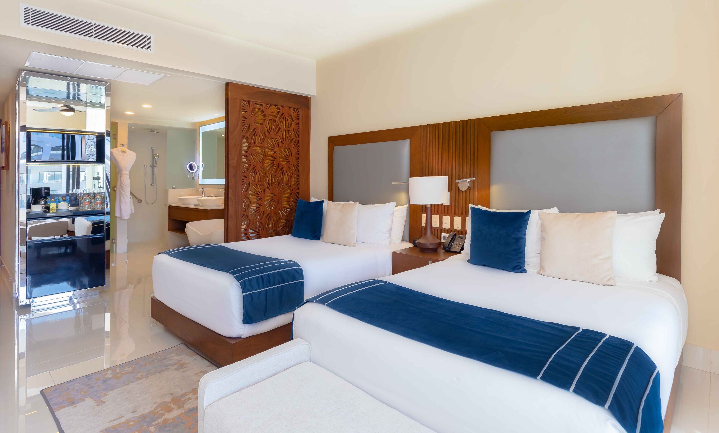 A hotel room with two beds, a bathroom, and a view of the city.