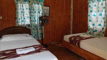 A bedroom with two beds, wooden flooring, and floral curtains.