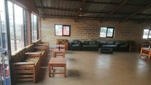 Una habitación amplia con suelo de baldosas, bancos de madera, un conjunto de sofás y un ventilador de techo.