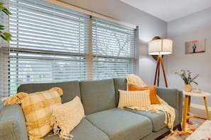 Relax in this inviting living room with a large sofa, floor lamp, and potted plant.