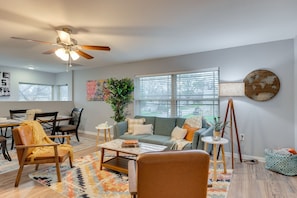 Relax in this inviting living room with a dining area, comfortable seating, and a large window with blinds.