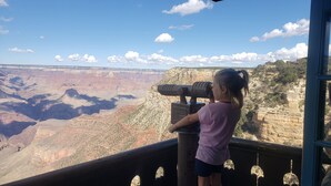 A person using a telescope to view a canyon landscape.