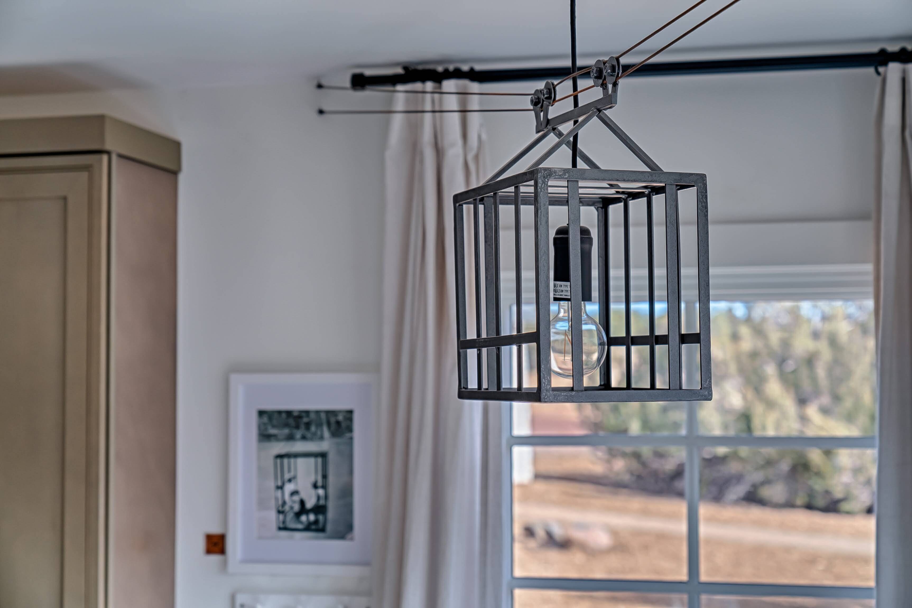 A room with a window, a framed picture on the wall, and a hanging light fixture.