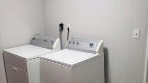 A laundry room with two front-loading washing machines and a dryer.