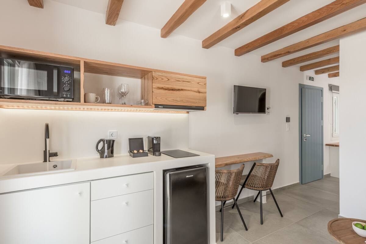 Eine moderne Küche mit Mikrowelle, Toaster und Kaffeemaschine. Ein Essbereich mit Korbstühlen und einem Tisch.