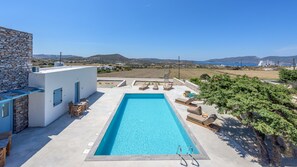 A rectangular swimming pool with a clear blue water, surrounded by lounge chairs and a small table. - Elements of Milos (Milos)