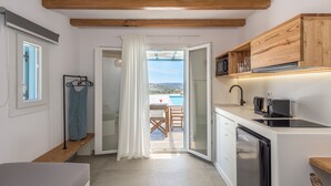 Cocina compacta con vista a una piscina y montañas, armarios de madera, microondas y cafetera.