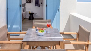 Un área de estar al aire libre con una mesa, sillas y vistas al interior.