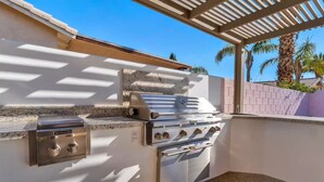 An outdoor kitchen with a built-in gas stove and a side burner, a grill, and a built-in sink. - Mango Manor - Close to festivals & tennis gardens! (Indio)