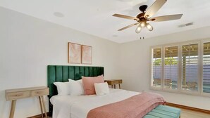 A bedroom with a bed, bedside tables, a ceiling fan, and a window with blinds. - Mango Manor - Close to festivals & tennis gardens! (Indio)