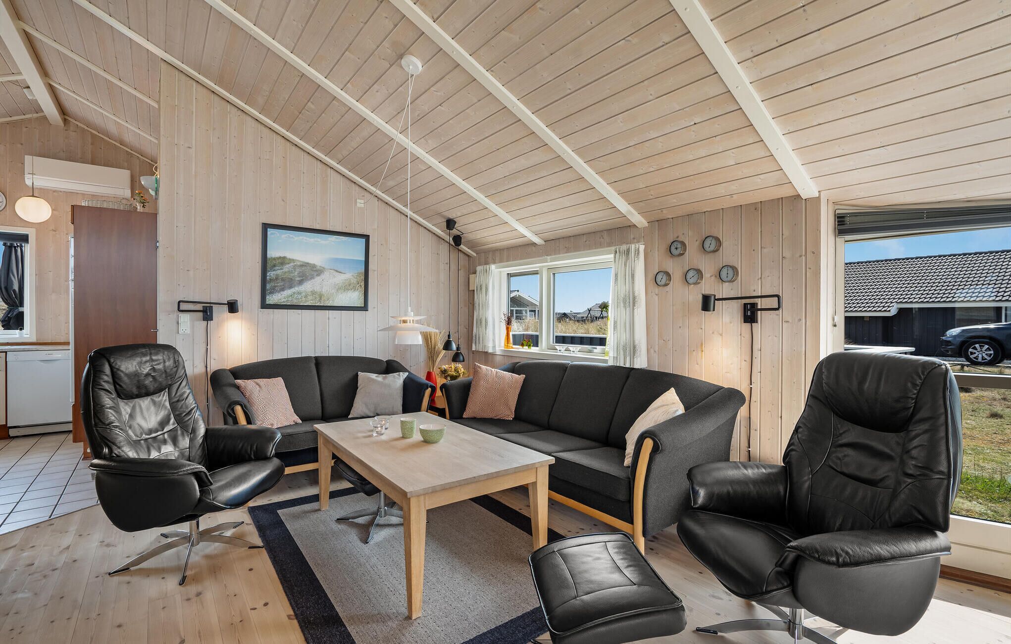 Una sala moderna con techo de madera, un juego de sofá, una mesa de comedor y vistas al exterior.
