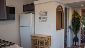 A kitchen with a white refrigerator, wooden table, and a wall-mounted art piece.