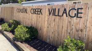 A wooden fence with "COASTAL CREEK VILLAGE" written on it.