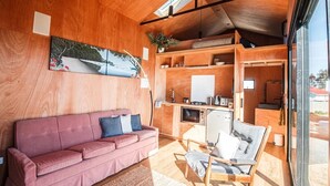 Una habitación acogedora con un sofá rosa, una mesa de comedor de madera y un ventanal grande.