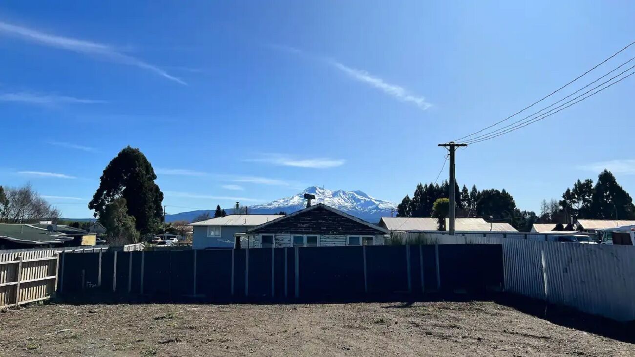 A fenced yard with a house and a mountain in the background.