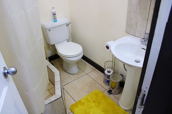 Un baño pequeño con inodoro, lavamanos y un tapete amarillo.