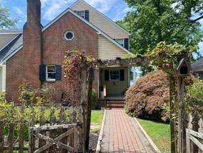 Stroll up to the charming entrance, flanked by a lush arbor and a beautifully manicured lawn.