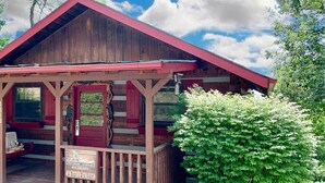 A wooden cabin with a porch, a red door, and a sign indicating a bed and eye wash. - Mountainside cabin with breathtaking views/hot tub/arcade/pet friendly (Pigeon Forge)