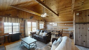 A cozy cabin-style room with a wooden ceiling, a sofa, a dining table, and a kitchen area. - Mountainside cabin with breathtaking views/hot tub/arcade/pet friendly (Pigeon Forge)