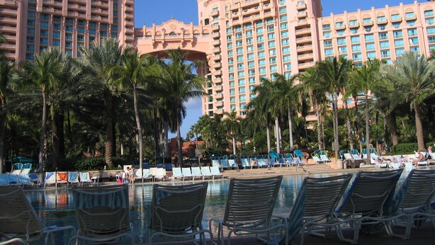 A resort with a large pool area, palm trees, and a prominent hotel building with multiple balconies. - Harborside Resort @ Atlantis 2 BR Sleep 6-8 (Nassau)