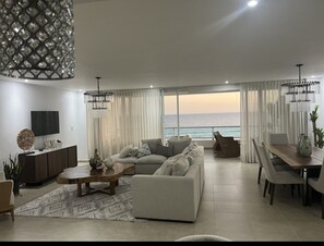 Relax in this serene living room with a comfortable sofa, flat-screen TV, and ocean views.