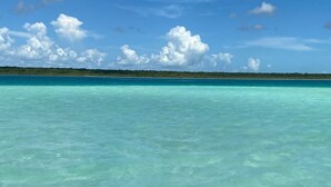 A clear view of turquoise waters with a distant shoreline and a clear sky.