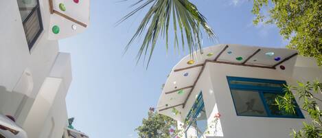 A building with white walls and colorful decorations, including a palm tree and a window with a blue frame.