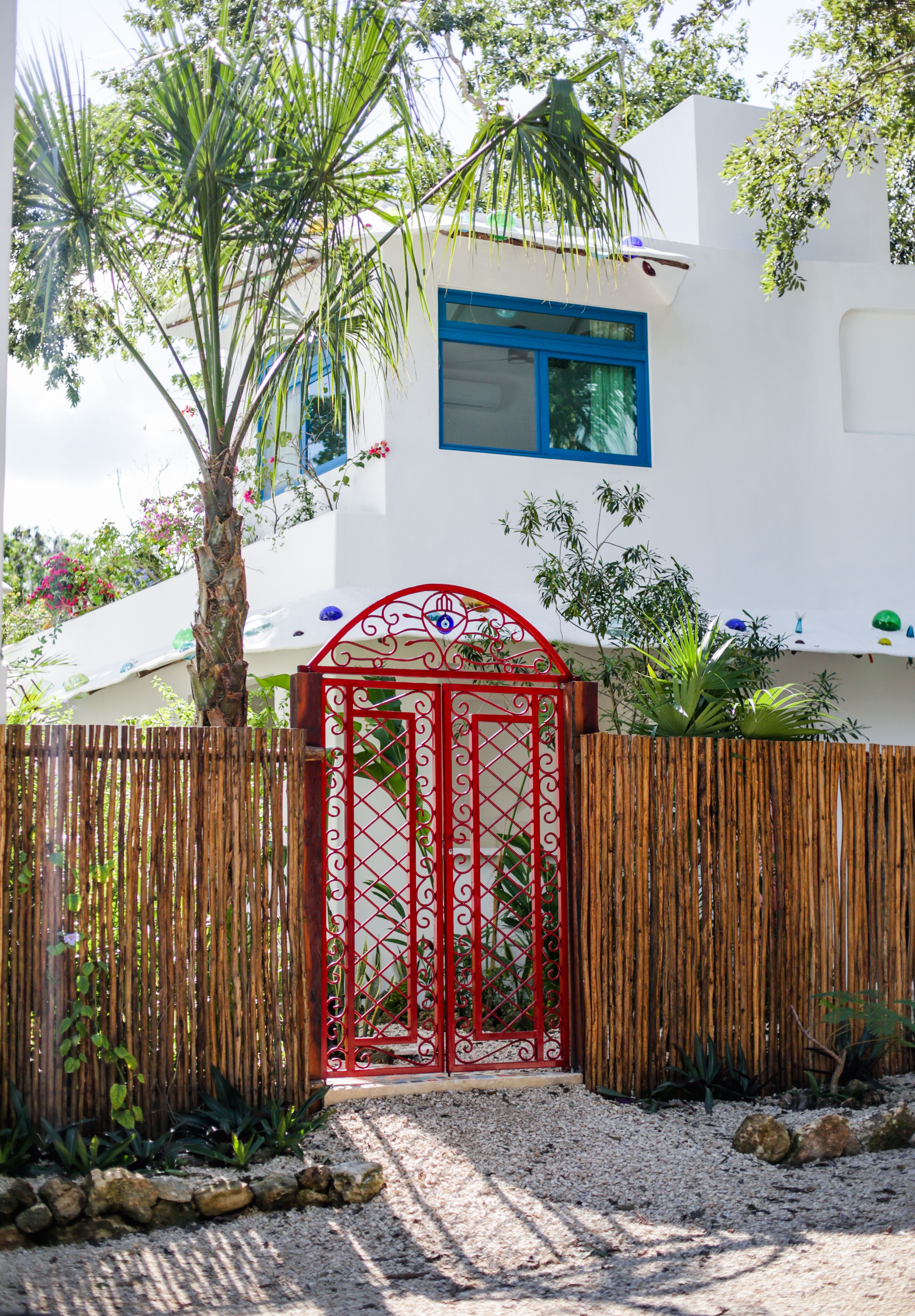 A white building with a blue window and a red gate.