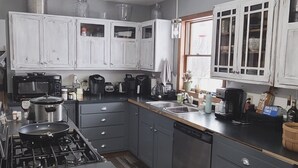 Una cocina con una isla central, armarios grises, una estufa y una lámpara colgante.