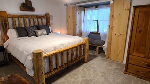 Una cama de madera con cabecera, mesitas de noche y una silla.