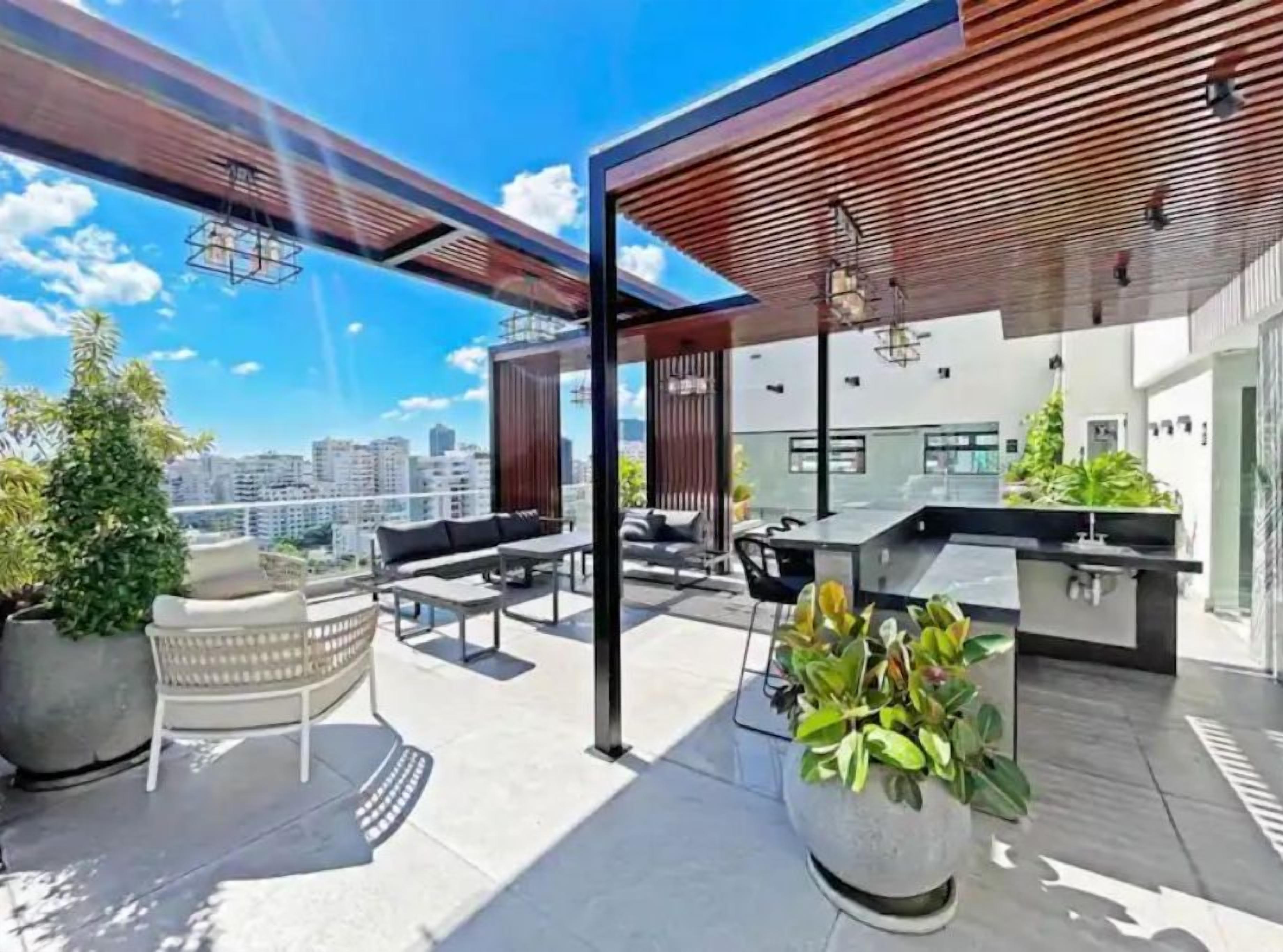A rooftop terrace with outdoor seating, a bar area, and potted plants.