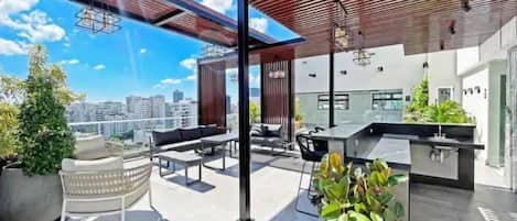 A rooftop terrace with outdoor seating, a bar area, and potted plants.