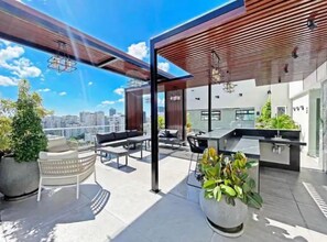 Een dakterras met buitenmeubilair, een bar en potplanten.