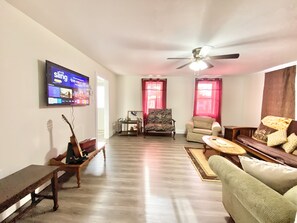 Un salon équipé d’un téléviseur à écran plat, d’un ventilateur de plafond et d’un banc en bois.