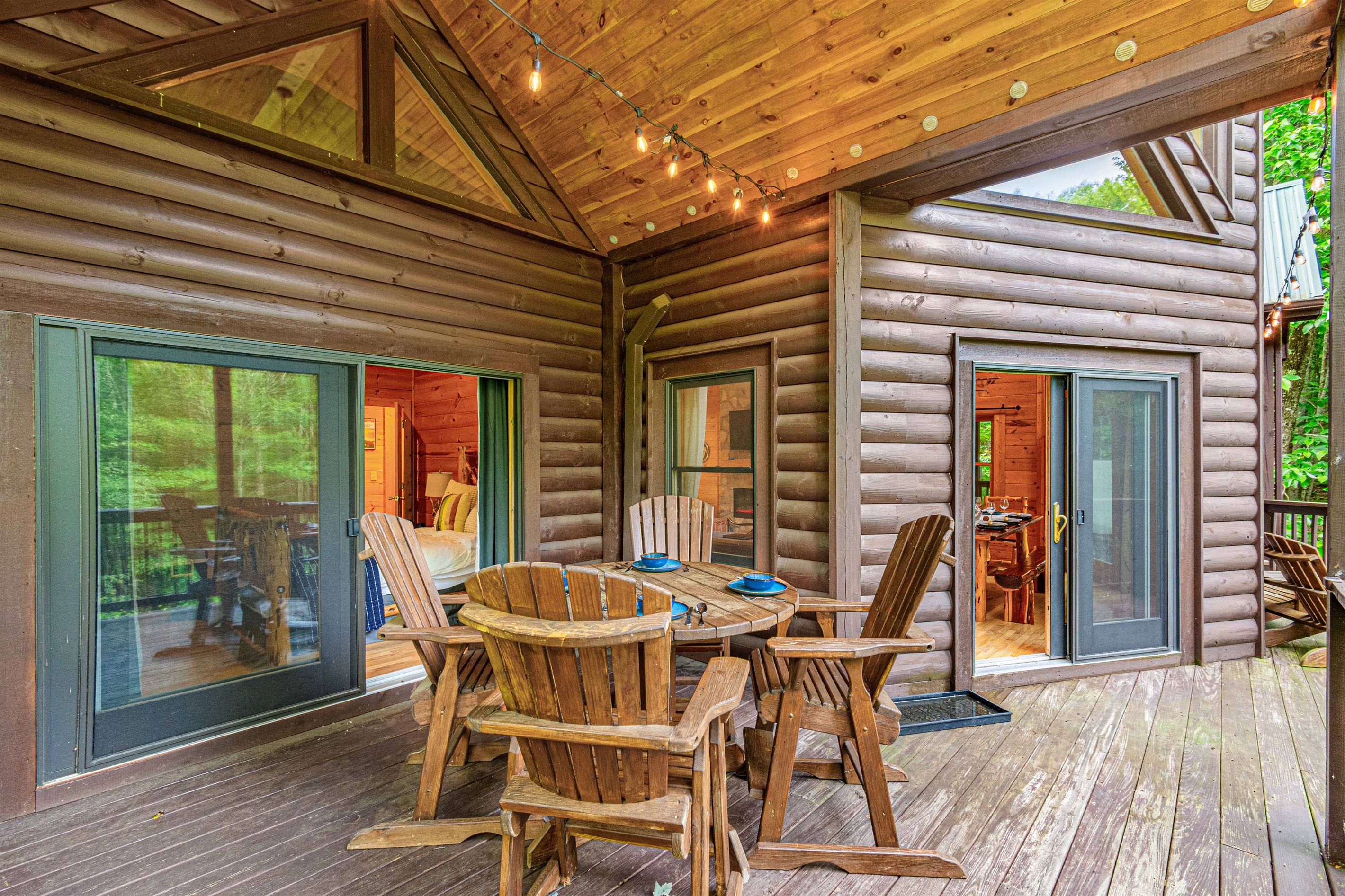 A log cabin with a wooden deck, outdoor seating, and large sliding glass doors.