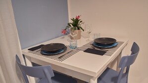 Une table à manger dressée avec des assiettes, des couverts et des verres, entourée de chaises bleues.