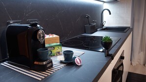 Une cuisine moderne équipée d’une machine à café, d’une boîte de thé, d’un évier et d’une petite plante en pot.