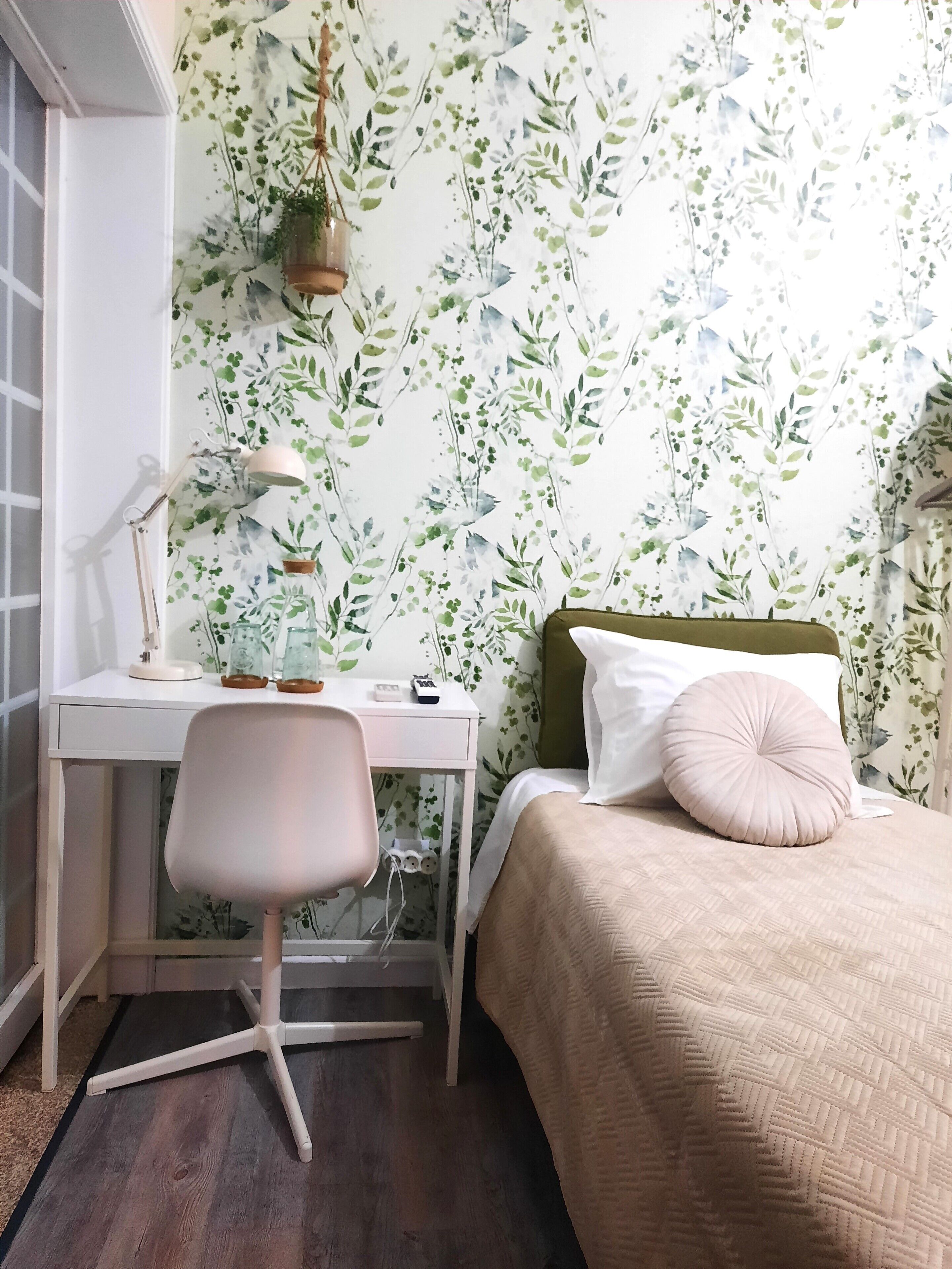 Een slaapkamer met een bed, een bureau en een stoel.