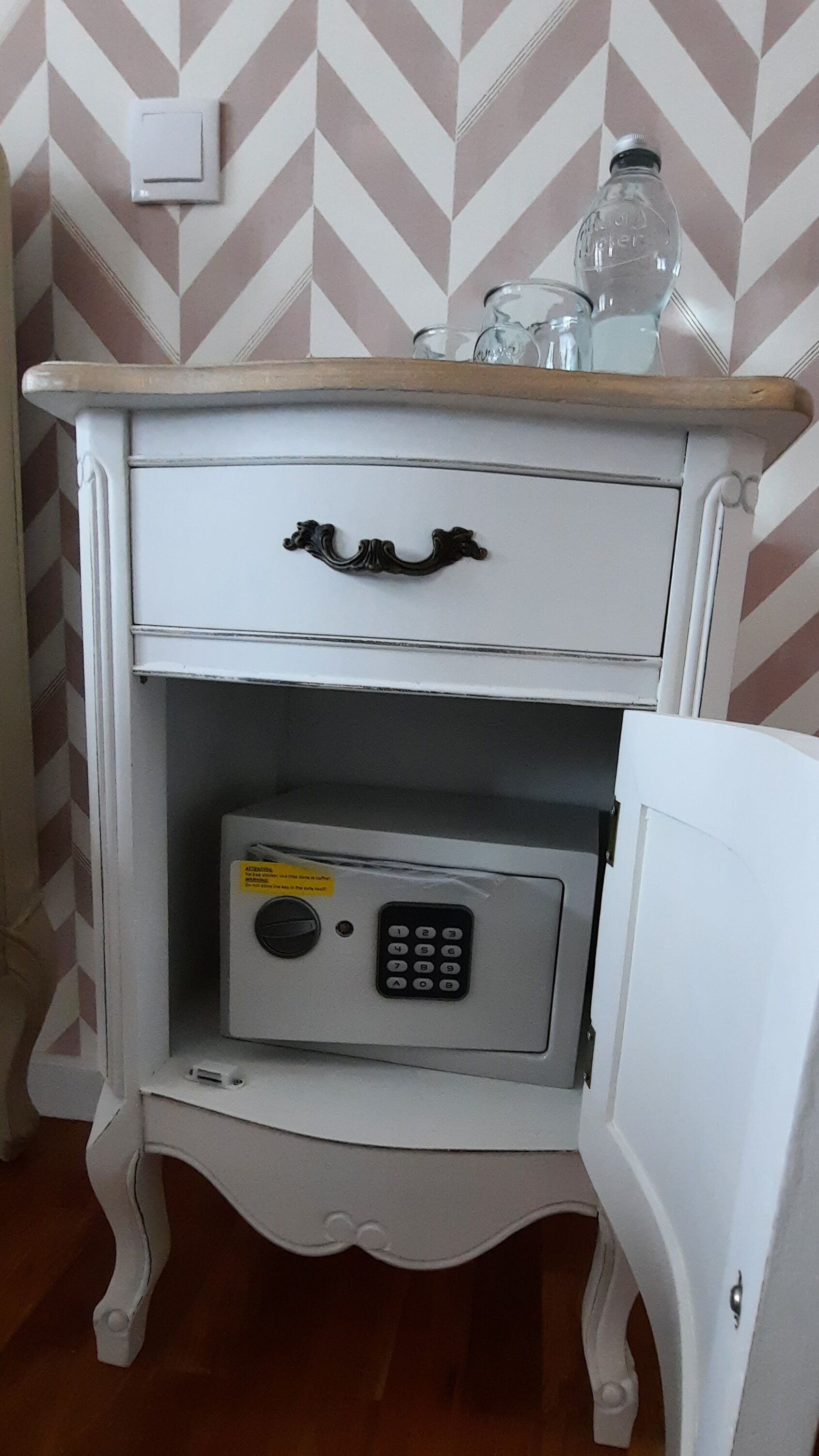 Un mueble blanco con tapa de madera, un cajón y una caja fuerte con teclado.