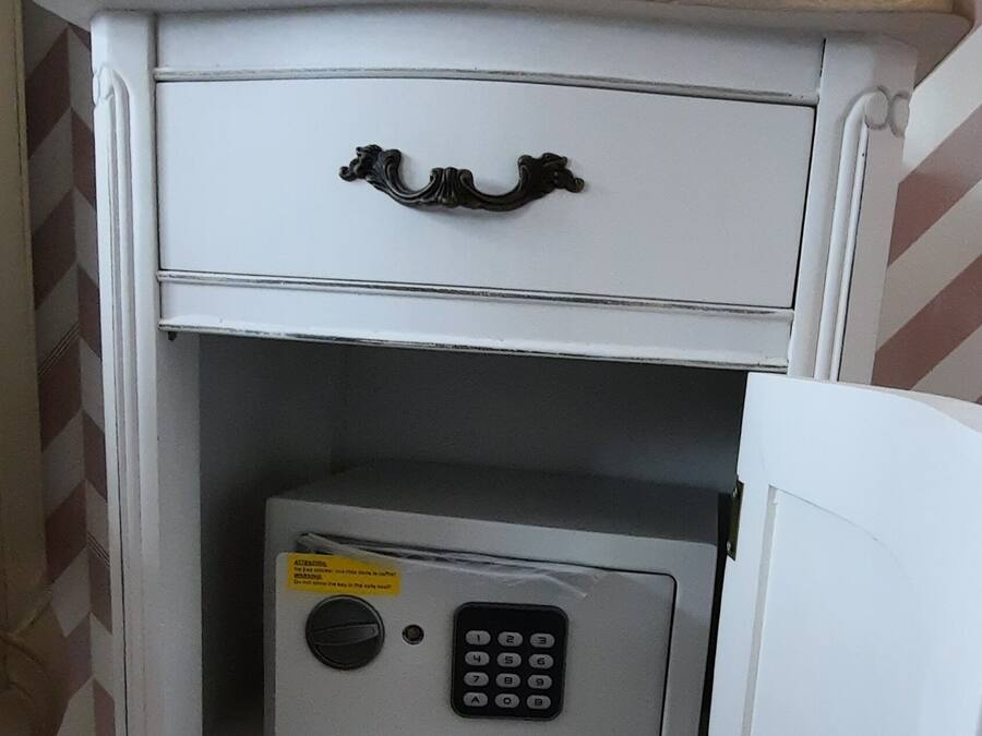 Un mueble blanco con tapa de madera, un cajón y una caja fuerte con teclado.