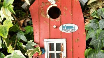A red birdhouse with a sign that reads "SMILING PLACES FOR BIRDS" and a small window.