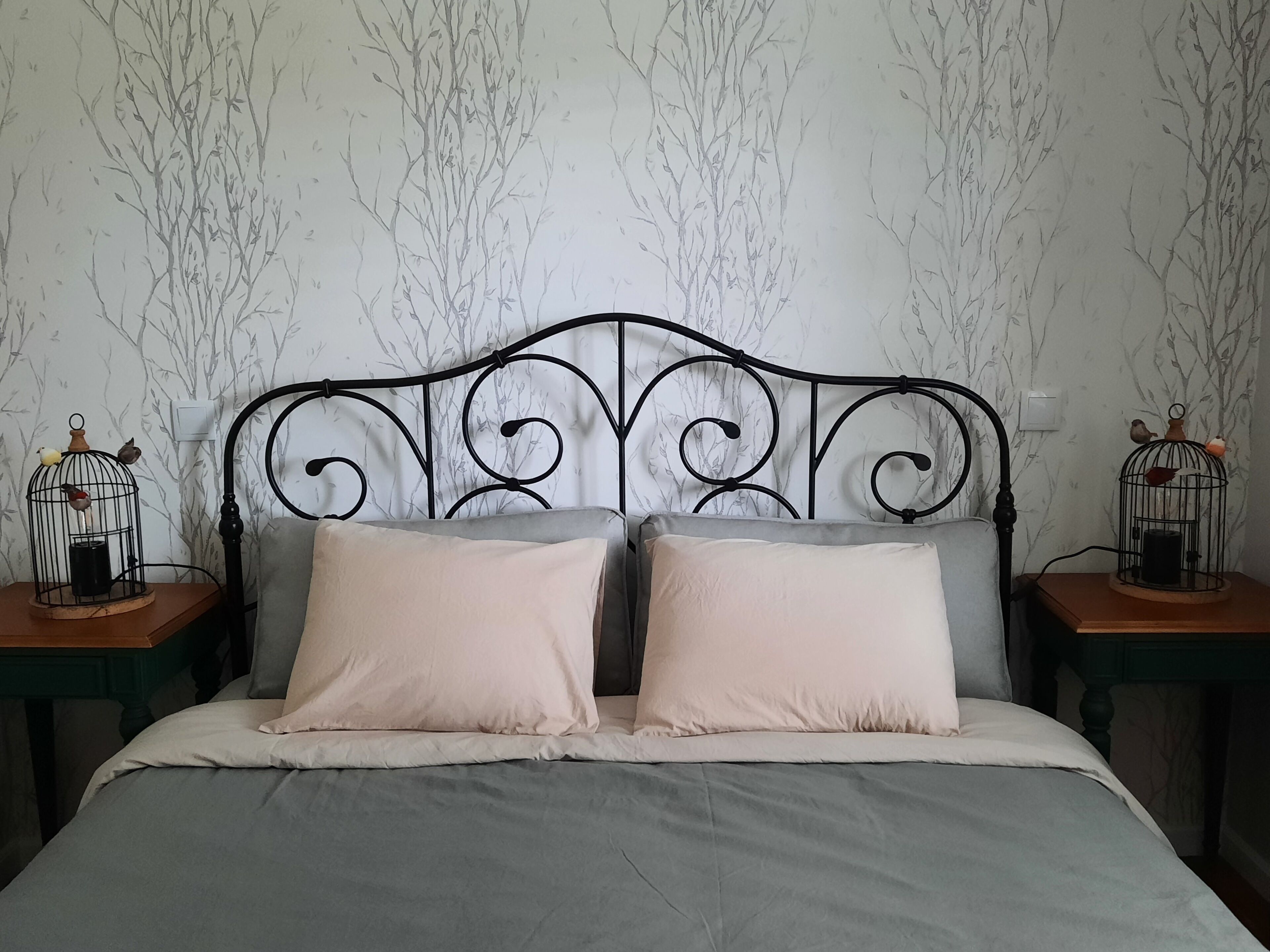 A bed with a metal headboard, two pillows, and two nightstands with birdcages.