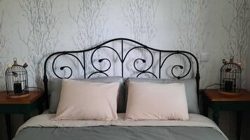 A bed with a metal headboard, two pillows, and two nightstands with birdcages.
