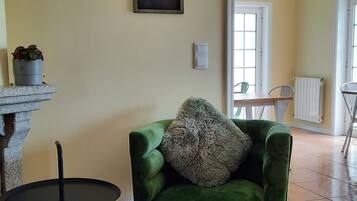 Een woonkamer met een groene fauteuil, een bijzettafeltje, een potplant en een inspirerende quote op de muur.