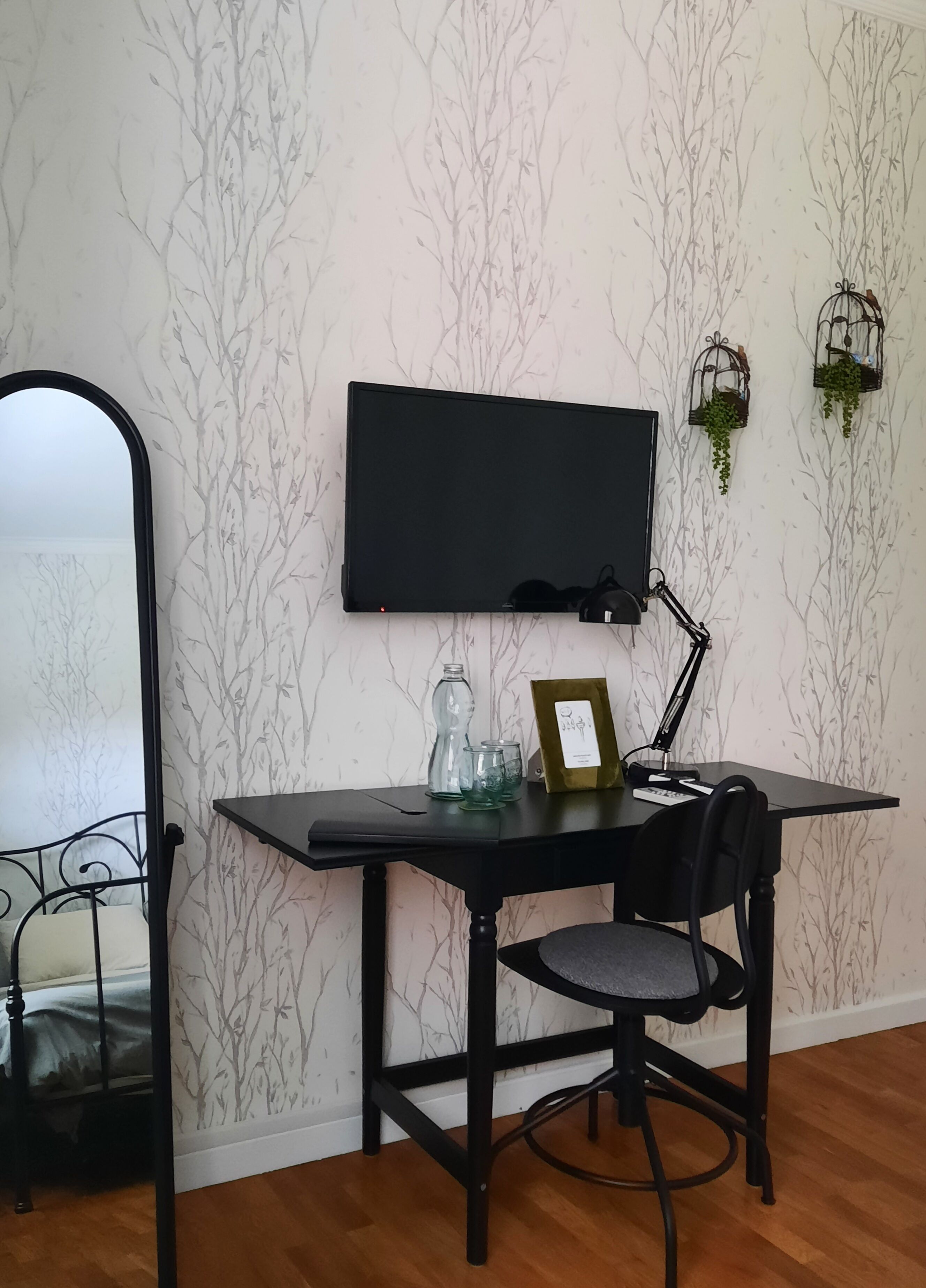 A small workspace with a desk, chair, and a wall-mounted TV.