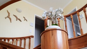 A wooden staircase with a central column and a flower arrangement on top. - Smiling Places (Vila do Conde)